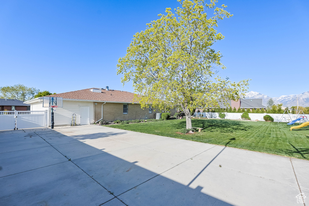 View of front of home featuring a gate, concrete driveway, fence, brick siding, and a front yard