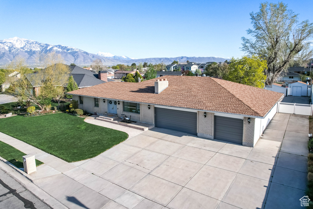 Single story home with a mountain view, a gate, concrete driveway, a garage, and a front yard