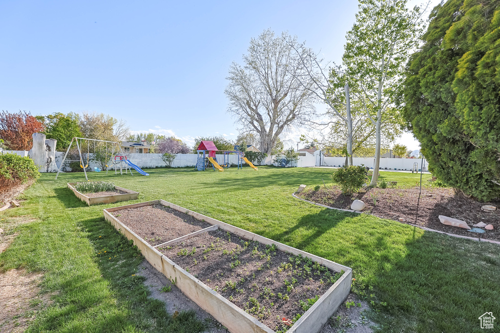 View of yard with a fenced backyard, a vegetable garden, and a playground