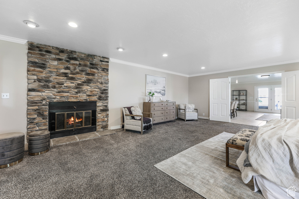 Living room with baseboards, a stone fireplace, carpet flooring, and crown molding