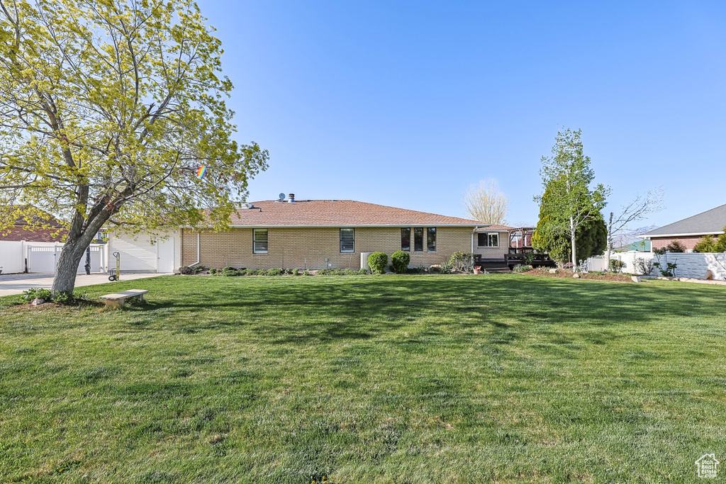Rear view of property with a lawn, fence, and brick siding