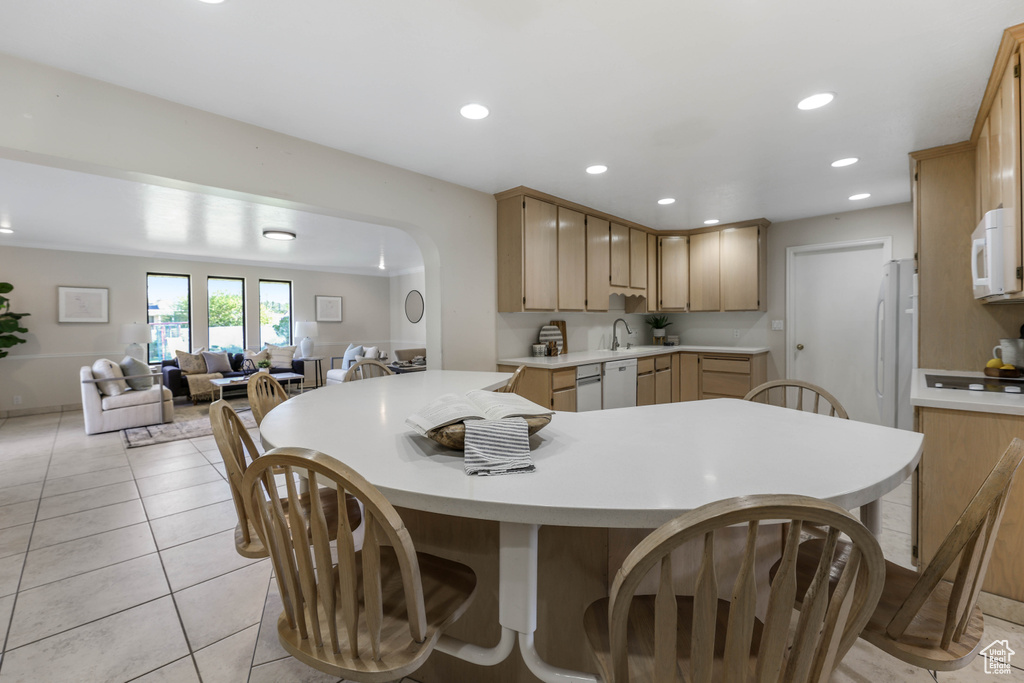 Kitchen with light countertops, a sink, white appliances, a peninsula, and open floor plan