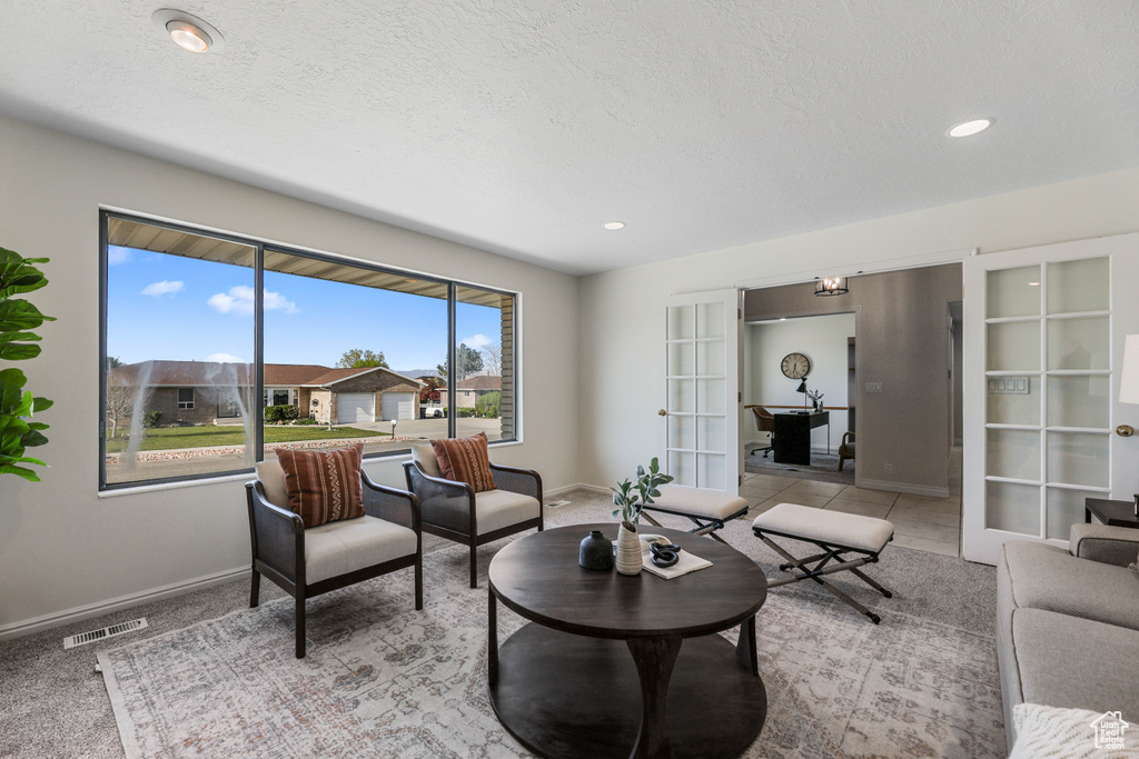 Living area featuring a textured ceiling, visible vents, baseboards, and french doors