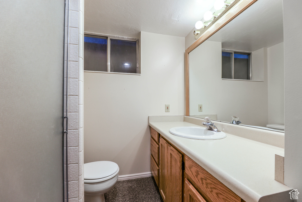 Bathroom featuring baseboards, vanity, and toilet