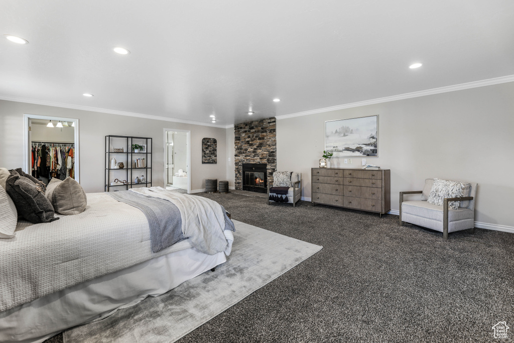 Bedroom featuring recessed lighting, ornamental molding, a walk in closet, baseboards, and a fireplace