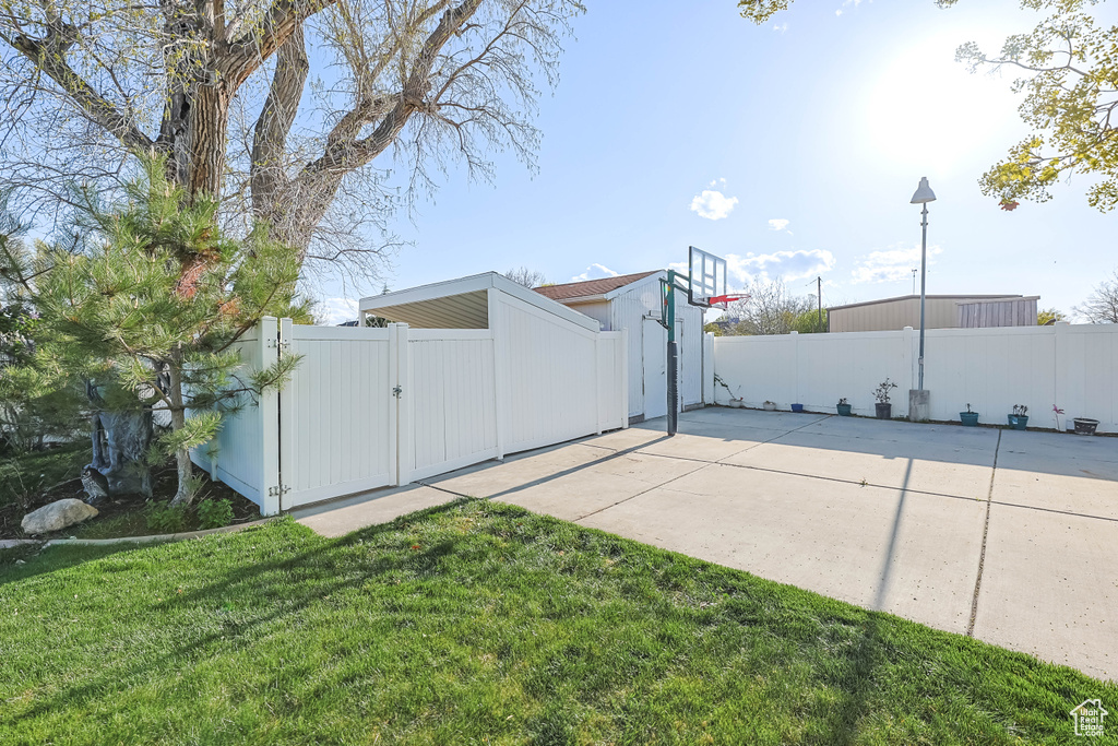 Exterior space featuring a gate, a yard, fence, and basketball hoop