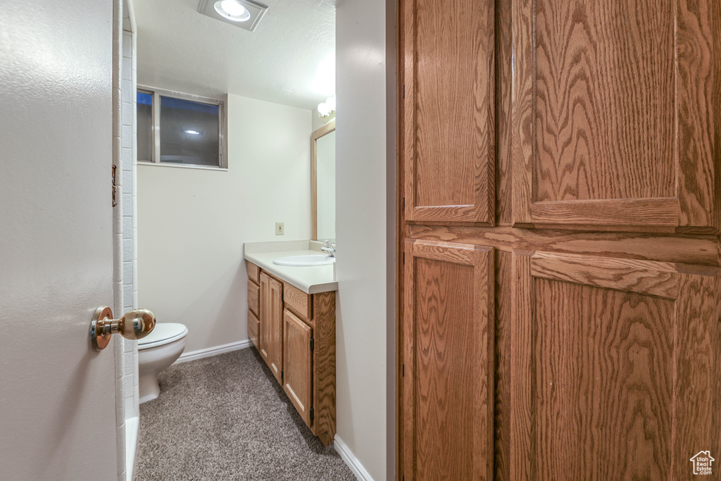 Bathroom featuring baseboards, toilet, and vanity