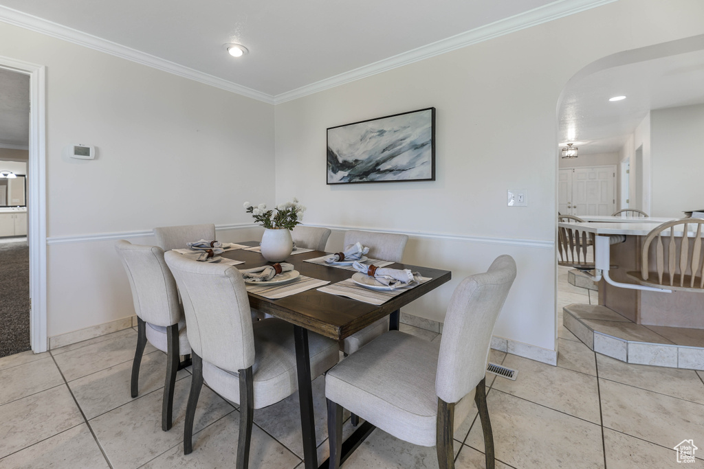 Dining space with arched walkways, baseboards, recessed lighting, crown molding, and light tile patterned floors