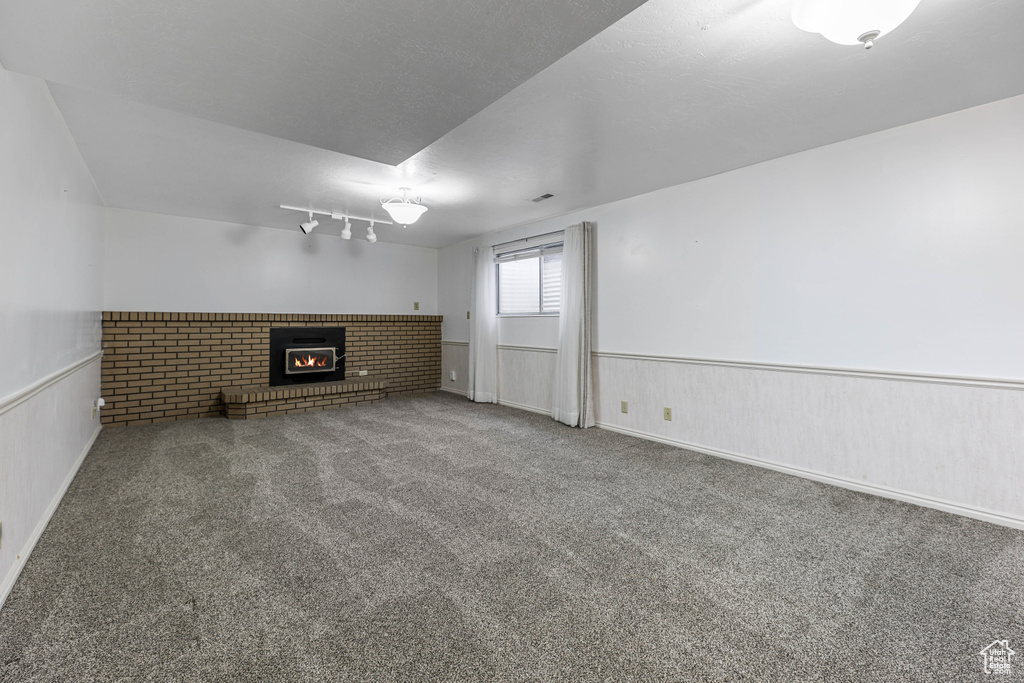 Unfurnished living room with carpet, a wainscoted wall, and a fireplace