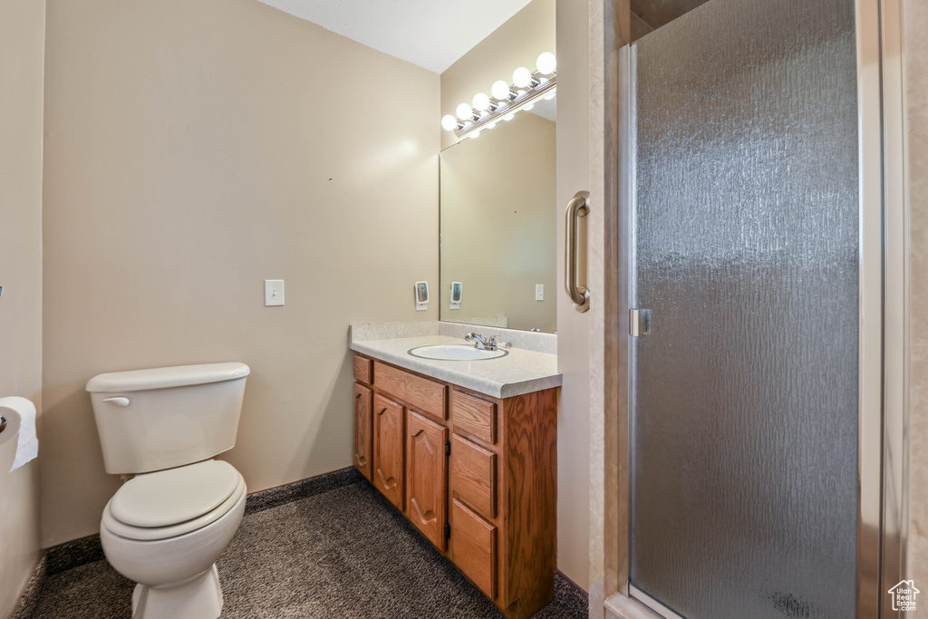 Bathroom with vanity, baseboards, a shower stall, and toilet