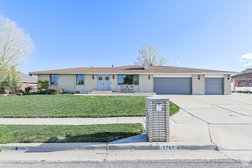 Ranch-style home with brick siding, an attached garage, a front yard, and concrete driveway
