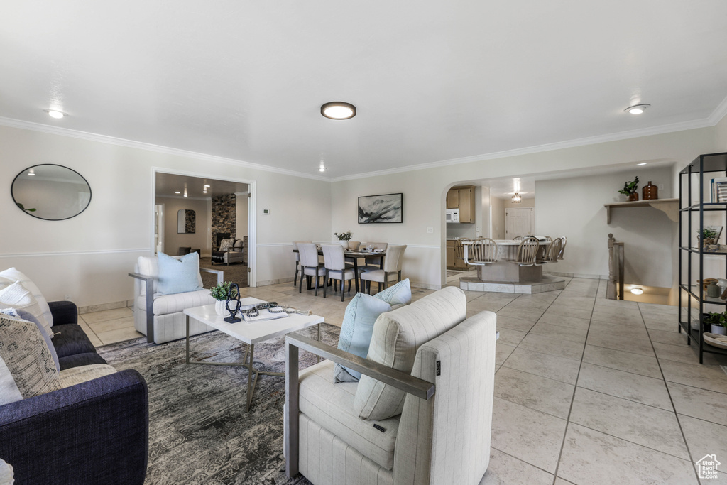 Living room featuring arched walkways, ornamental molding, and light tile patterned floors
