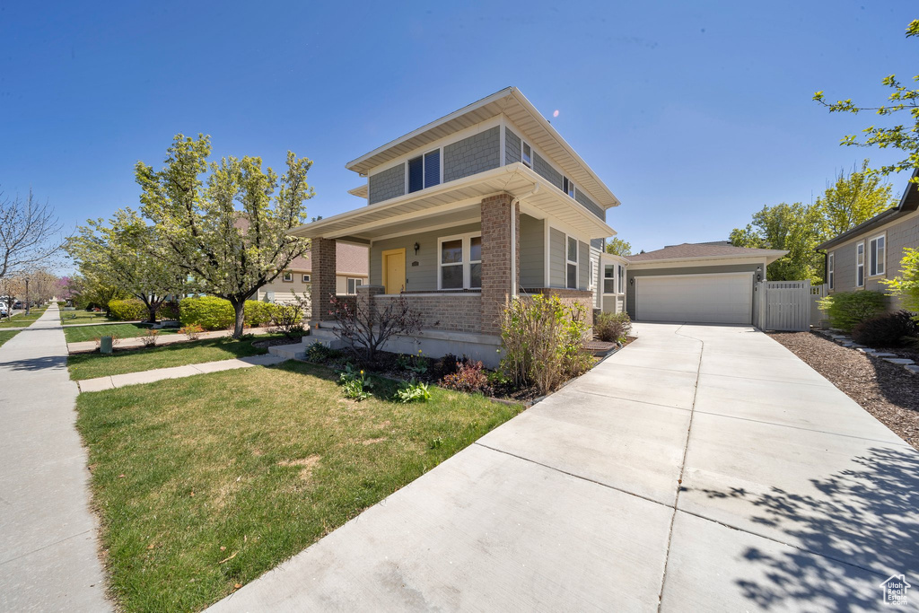 View of front of home with a front lawn, concrete driveway, a porch, brick siding, and a garage