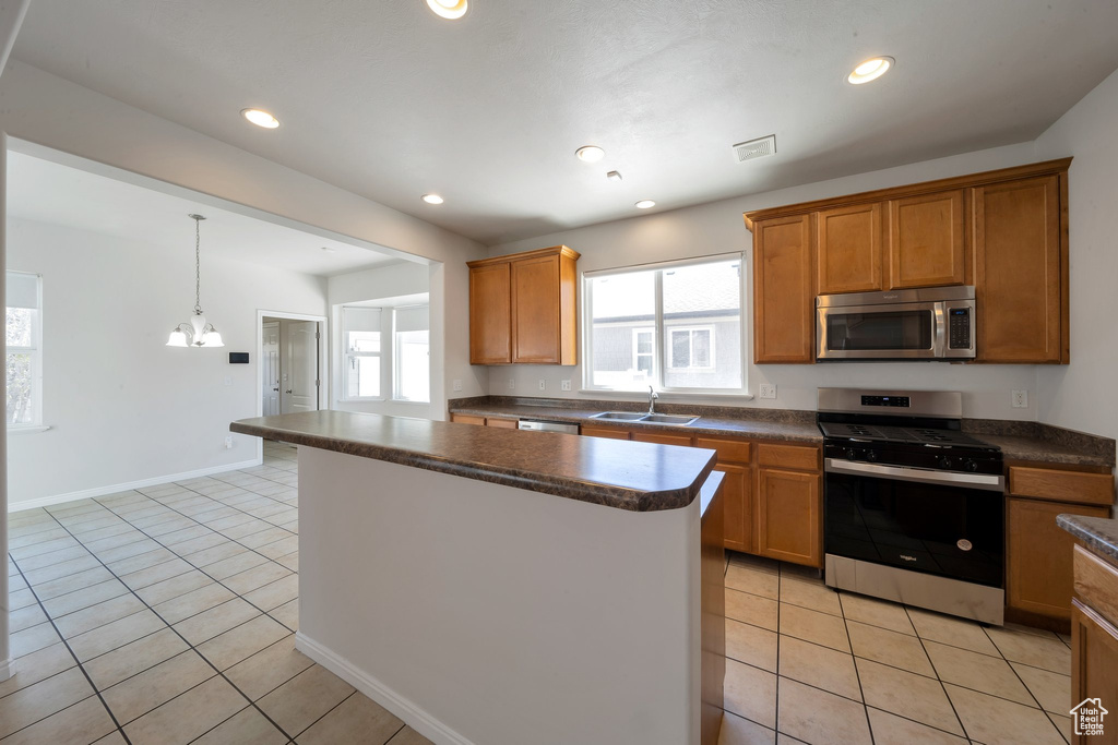 Kitchen with stainless steel appliances, dark countertops, a healthy amount of sunlight, a sink, and light tile patterned flooring