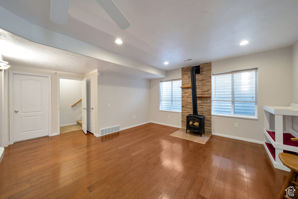 Below grade area featuring wood finished floors, a wood stove, visible vents, baseboards, and stairs