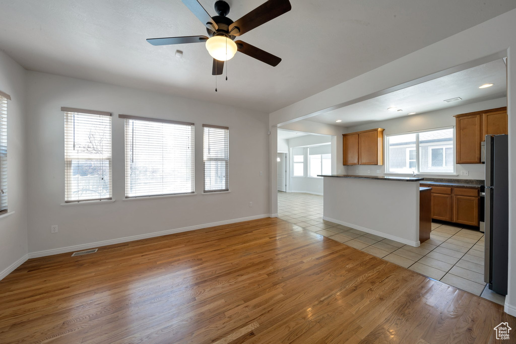Unfurnished living room with ceiling fan, baseboards, light wood finished floors, and visible vents