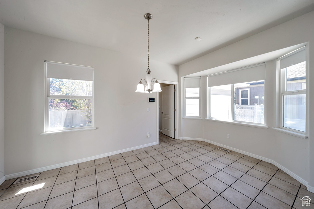 Spare room featuring baseboards, light tile patterned flooring, a chandelier, and a healthy amount of sunlight