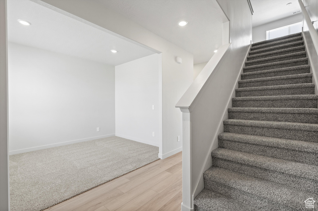 Stairway with wood finished floors and recessed lighting