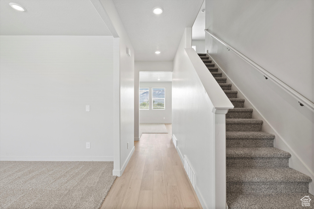 Staircase with recessed lighting and wood finished floors