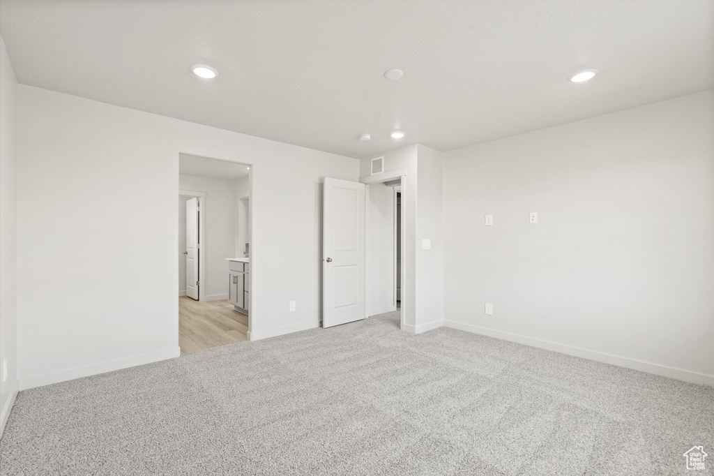Empty room with light colored carpet and recessed lighting