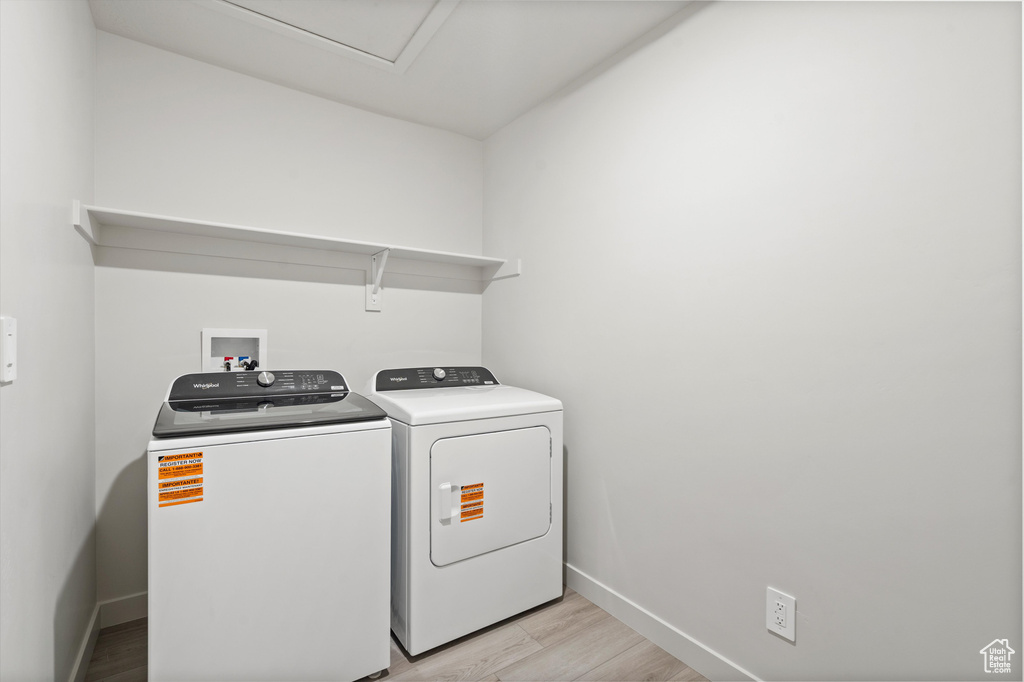 Laundry room featuring washing machine and dryer and light wood-type flooring