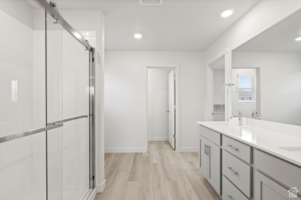 Full bath featuring a shower stall, double vanity, wood finished floors, and recessed lighting
