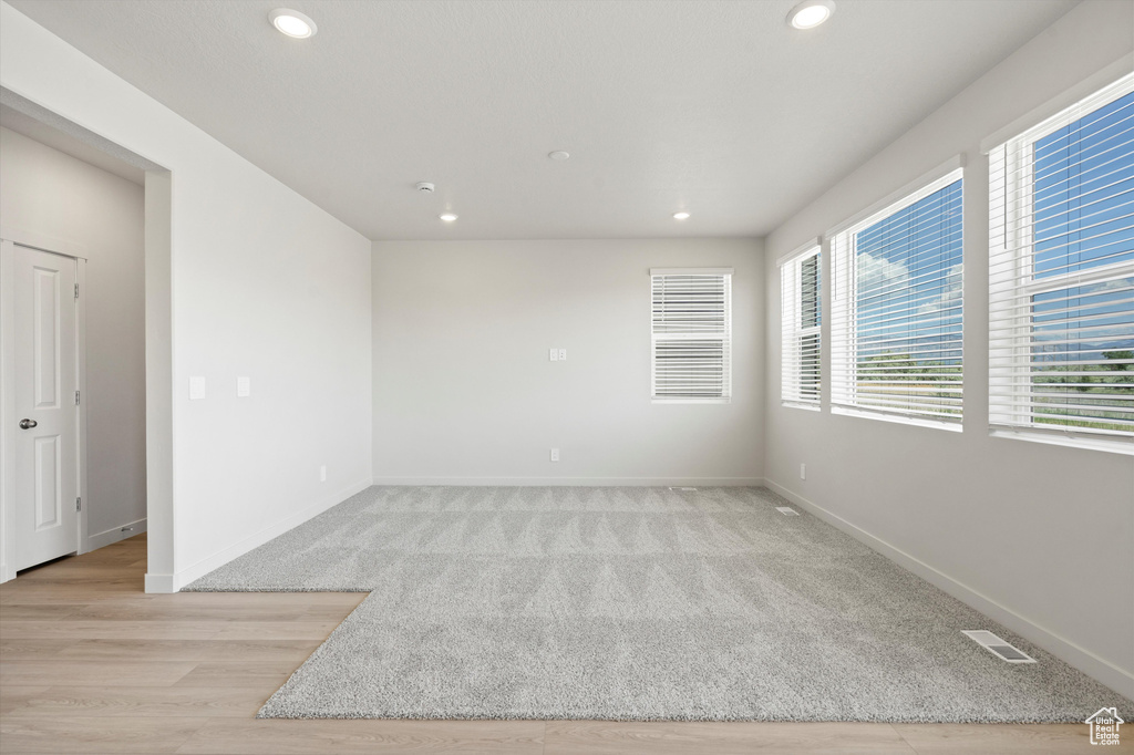 Empty room with recessed lighting, light colored carpet, and light wood-type flooring