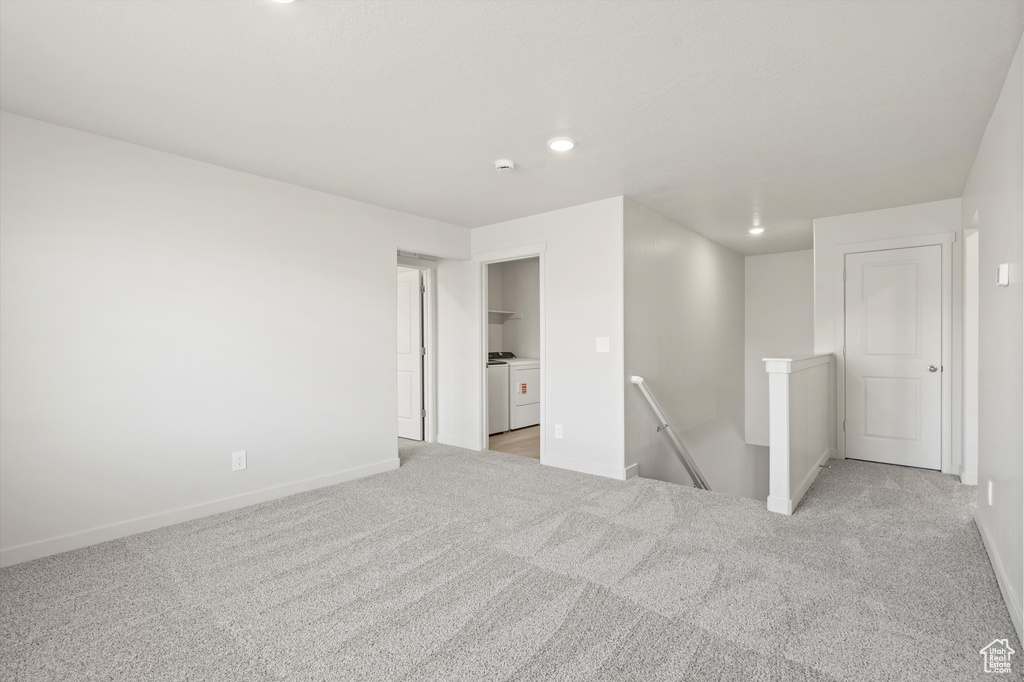 Empty room with separate washer and dryer, light colored carpet, and recessed lighting