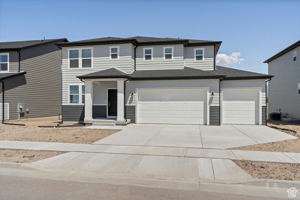 View of front of house featuring driveway, an attached garage, and a shingled roof