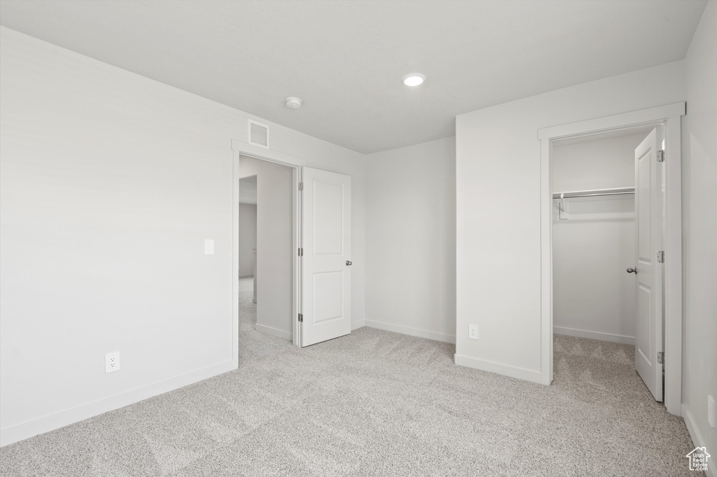 Unfurnished bedroom with carpet flooring, a walk in closet, a closet, and recessed lighting
