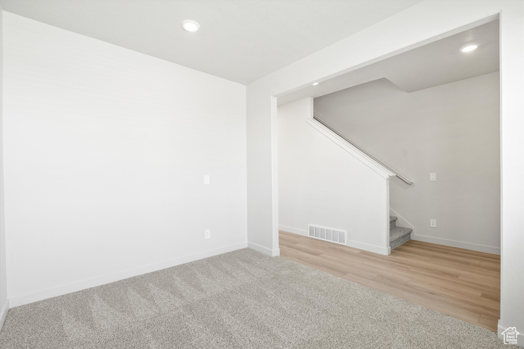 Below grade area featuring stairs, recessed lighting, wood finished floors, and carpet
