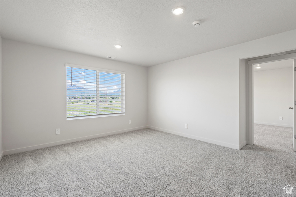 Empty room featuring carpet flooring, a smoke detector, and recessed lighting