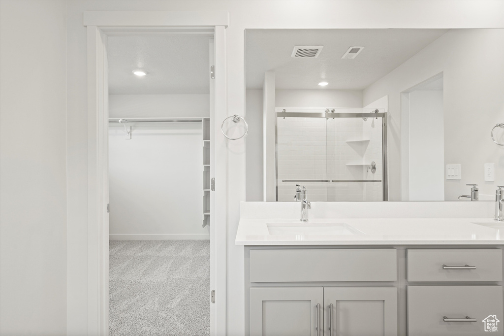Bathroom featuring a shower stall, double vanity, and a spacious closet