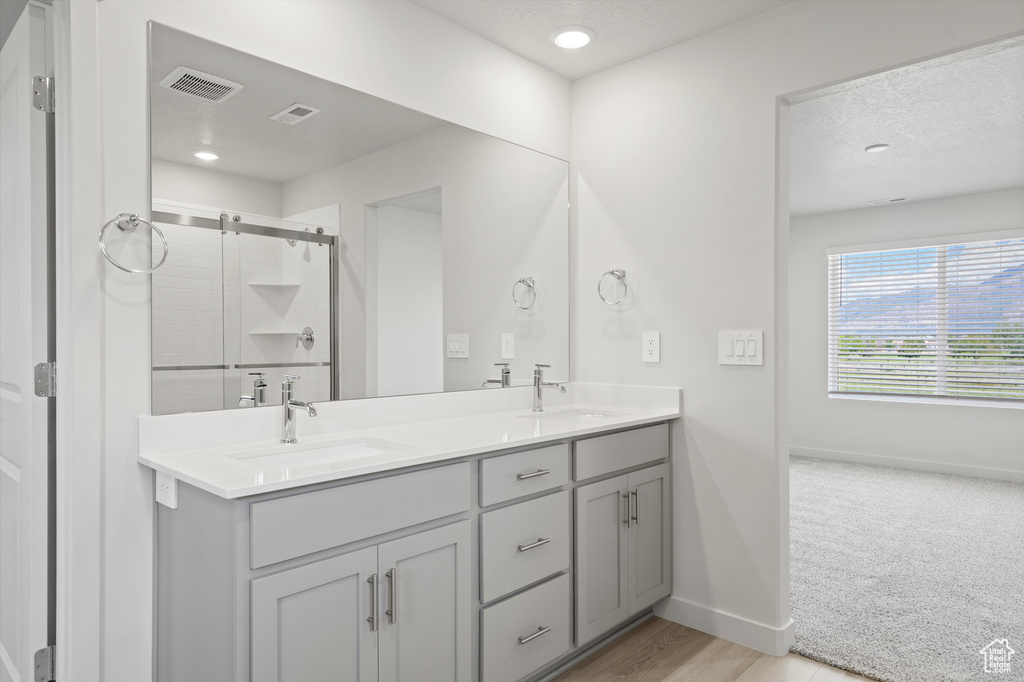 Bathroom featuring double vanity, a shower stall, a textured ceiling, and recessed lighting