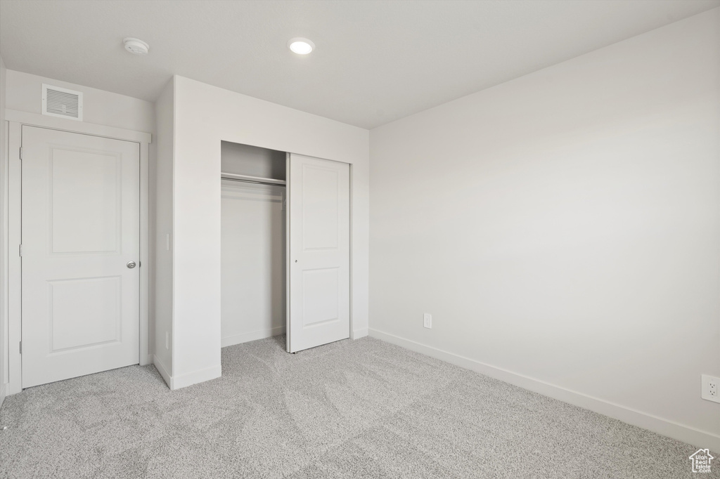 Unfurnished bedroom with light carpet, a closet, and recessed lighting
