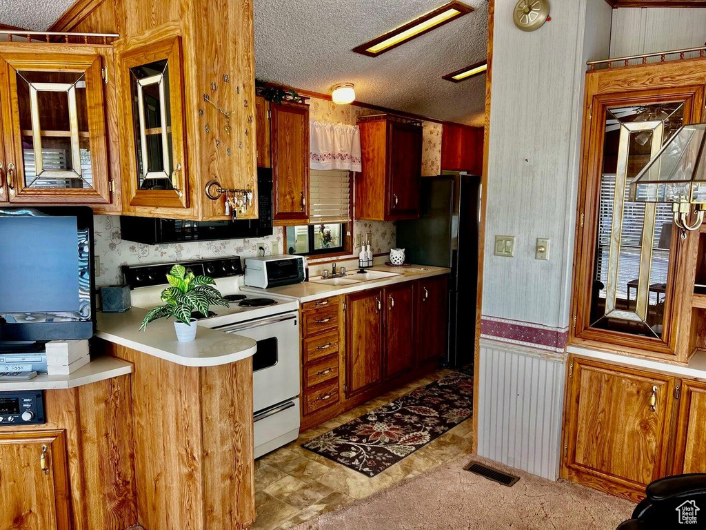 Kitchen with light countertops, visible vents, a sink, white electric range oven, and a textured ceiling
