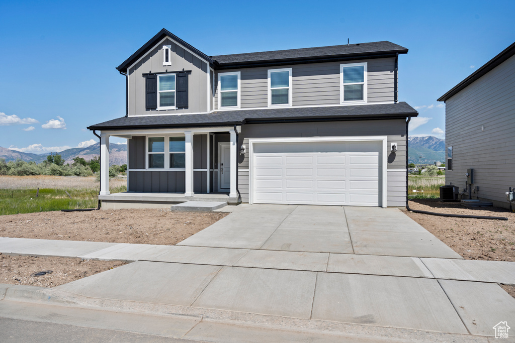 View of front facade featuring a porch, concrete driveway, a mountain view, an attached garage, and cooling unit
