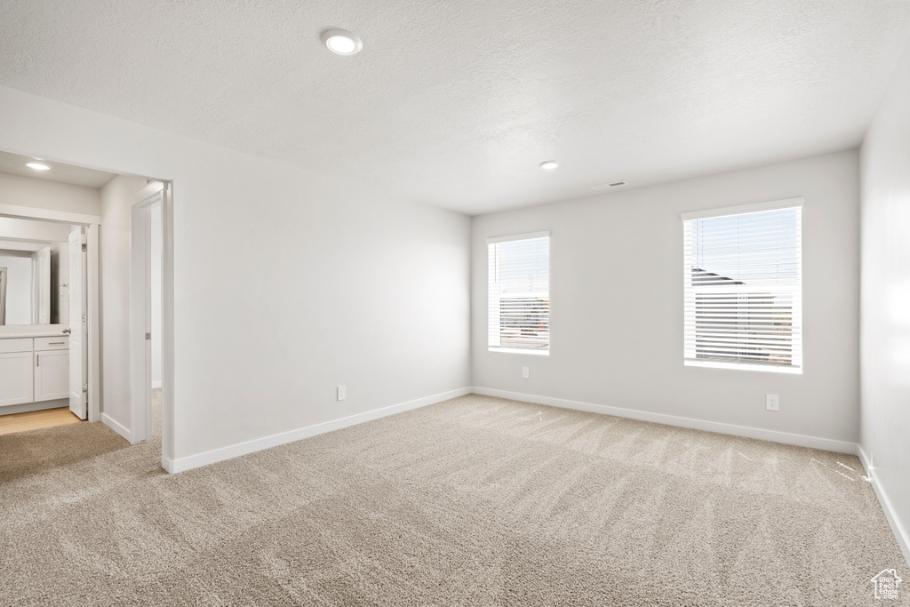 Empty room with light colored carpet, baseboards, and recessed lighting