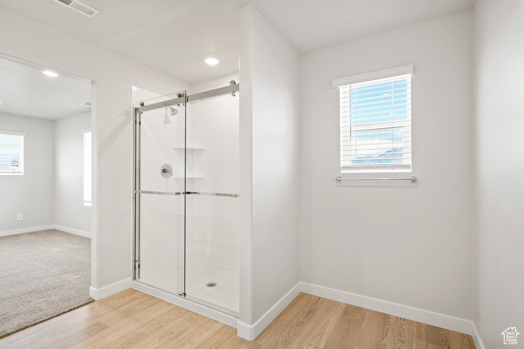 Bathroom with a shower stall, baseboards, wood finished floors, and recessed lighting