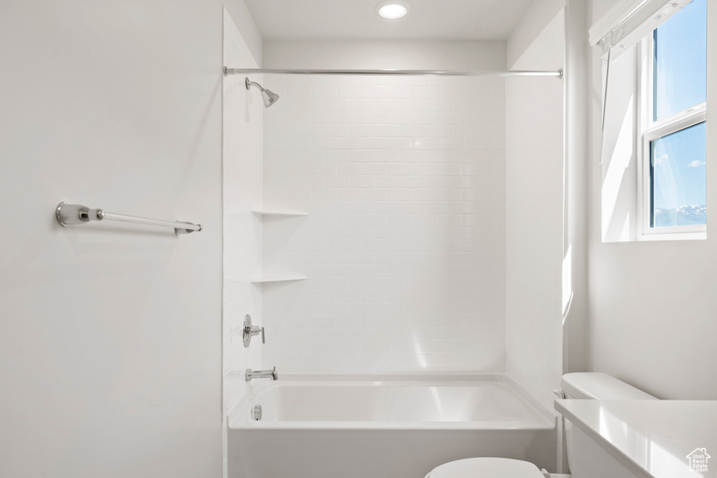 Bathroom with healthy amount of natural light, toilet, and bathtub / shower combination