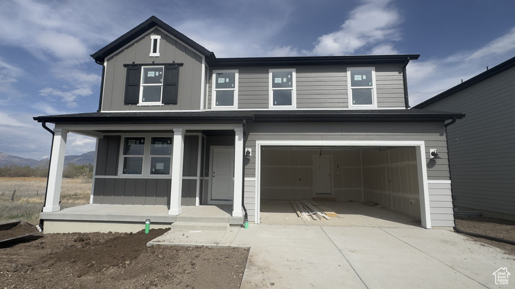 View of front of property with board and batten siding, a garage, driveway, a porch, and a mountain view