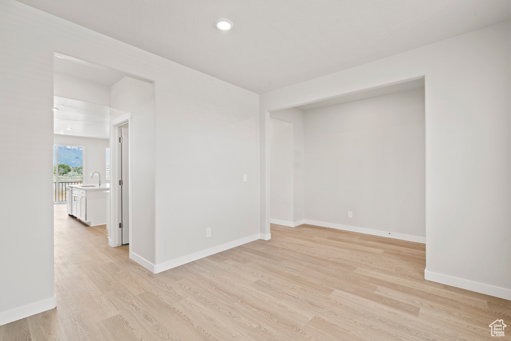 Unfurnished room featuring light wood-style flooring, baseboards, recessed lighting, and a sink
