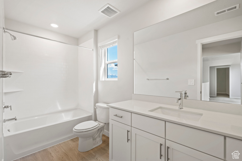Bathroom with toilet, wood finished floors, vanity, shower / washtub combination, and recessed lighting