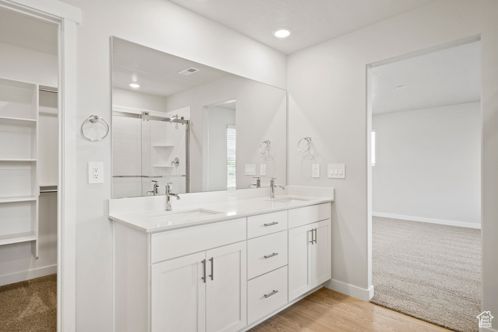 Full bathroom featuring a spacious closet, double vanity, a shower stall, baseboards, and recessed lighting