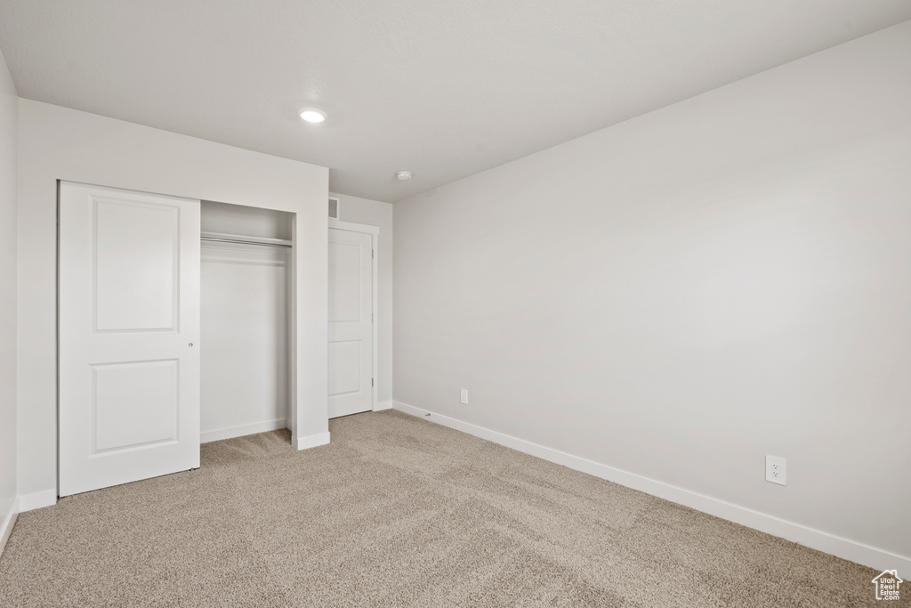 Unfurnished bedroom featuring light carpet, baseboards, a closet, and recessed lighting