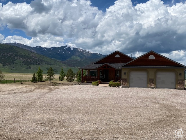 View of front of property with driveway, a mountain view, covered porch, a garage, and stone siding