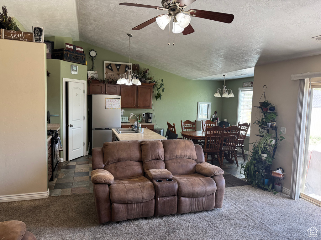 Living area with baseboards, dark colored carpet, a textured ceiling, and ceiling fan with notable chandelier