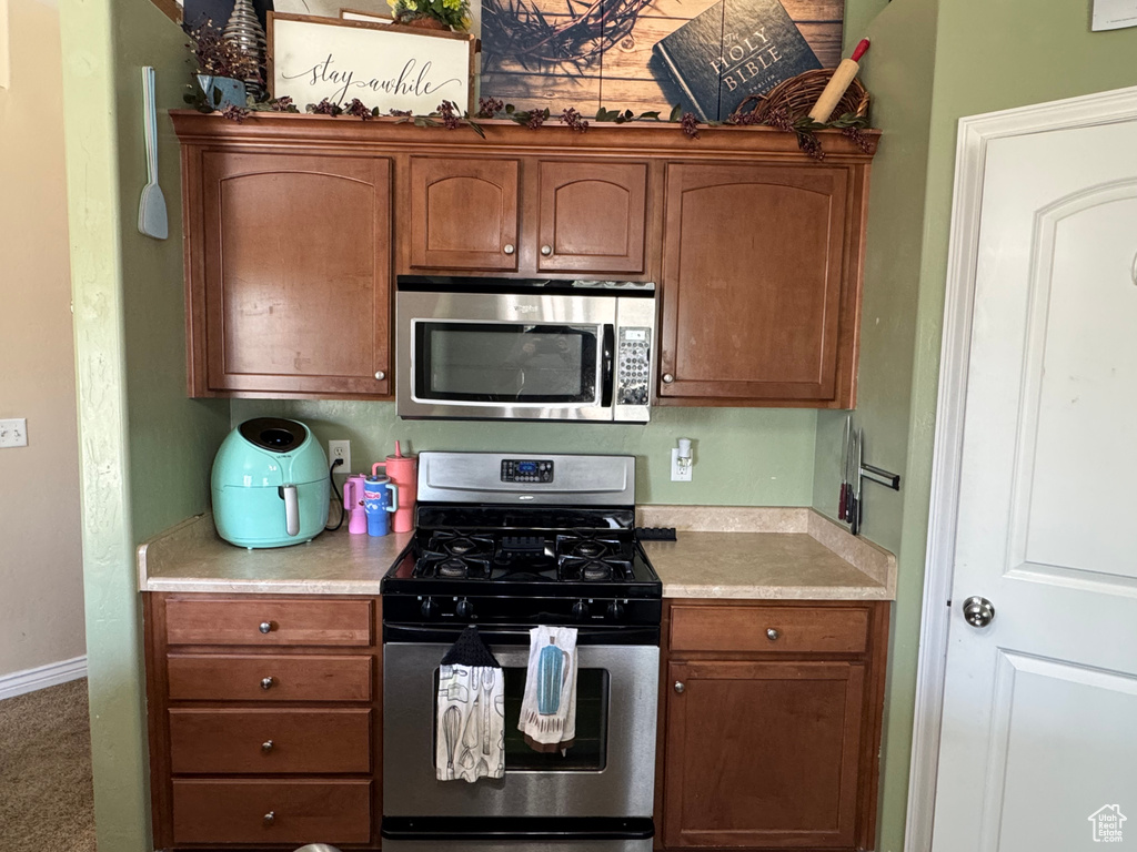 Kitchen featuring stainless steel appliances, light countertops, baseboards, and brown cabinets