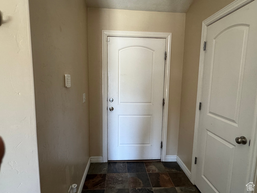 Doorway to outside featuring baseboards and stone finish flooring