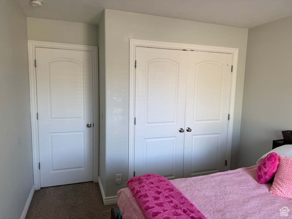 Bedroom with dark carpet, baseboards, and a closet